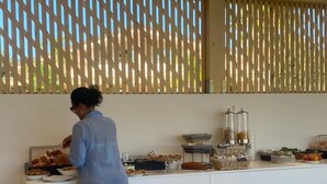 A person serving food at a buffet with various dishes and containers on a counter. - Resort Agave Blu (Ricadi)