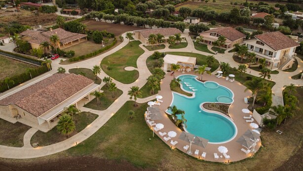 An aerial view of a residential area with a swimming pool surrounded by lounge chairs and umbrellas. - Resort Agave Blu (Ricadi)