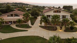 A residential area with a central paved walkway, surrounded by houses with balconies and palm trees. - Resort Agave Blu (Ricadi)