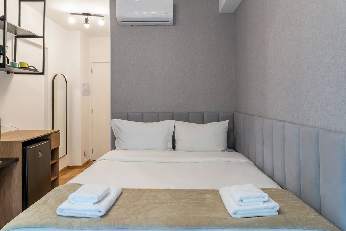 Ein Hotelzimmer mit einem Bett, einem Schreibtisch, einem Spiegel und einer Klimaanlage.