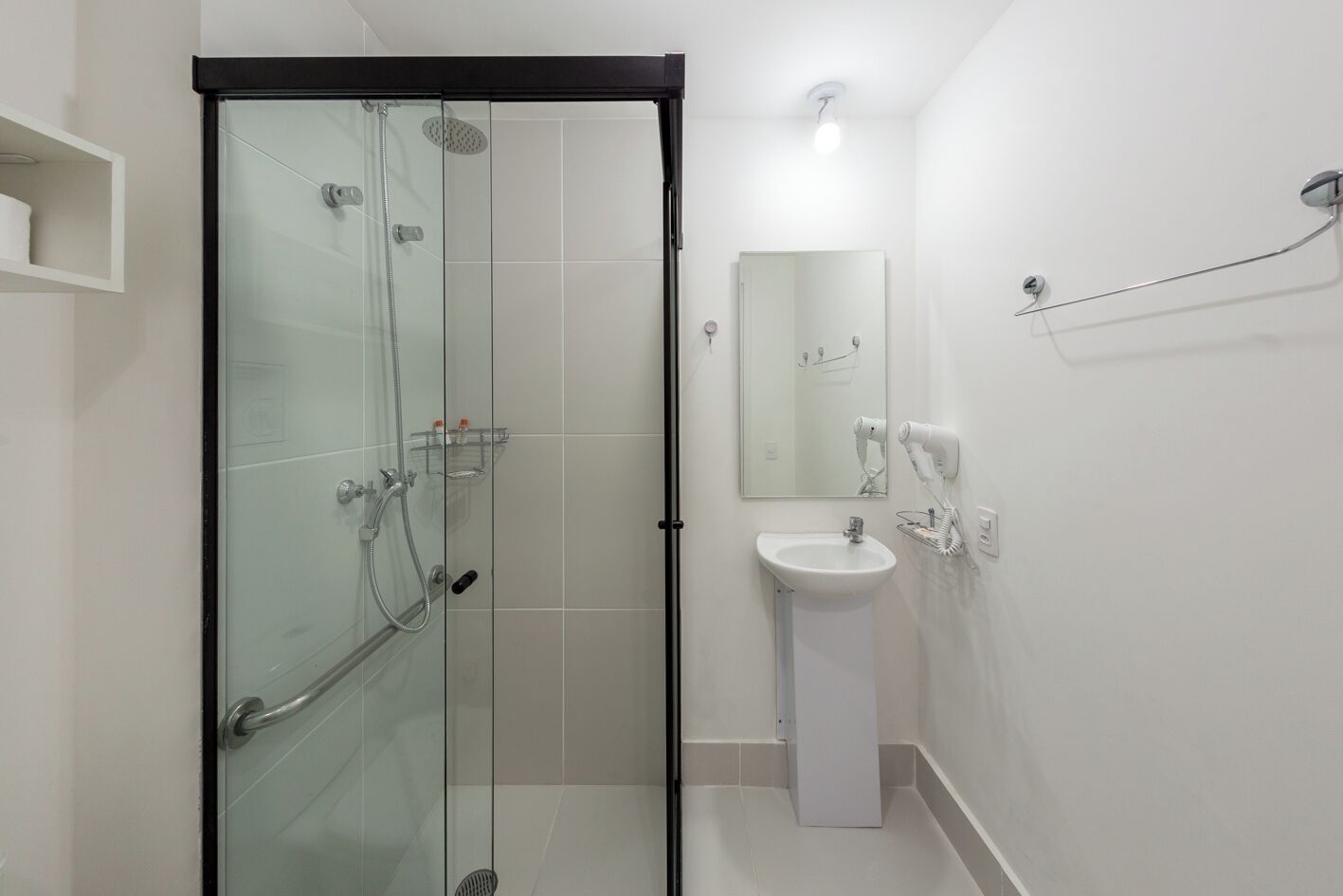 A modern bathroom with a glass shower enclosure, a white sink, and a mirror.