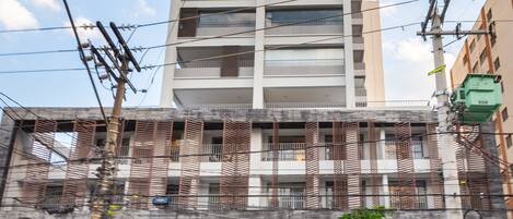 Un edificio de varias plantas con un diseño arquitectónico moderno, que cuenta con balcones con barandillas de madera y un frente de vidrio.