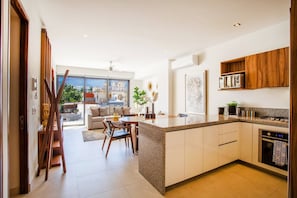 A modern kitchen with a central island, wooden cabinets, and a view to the outside. - Versalles Retreat | Modern 2-BR w/ Gym & BBQ (Puerto Vallarta)
