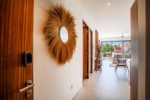 A hallway with a wooden door, a wall-mounted mirror, and a view of a balcony with outdoor furniture. - Versalles Retreat | Modern 2-BR w/ Gym & BBQ (Puerto Vallarta)
