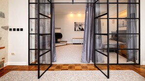 A bedroom with a large sliding door, a bed, a nightstand, a dresser, and a wall-mounted light fixture. - Stunning Old Town Getaway with Sauna! (Tallinn)