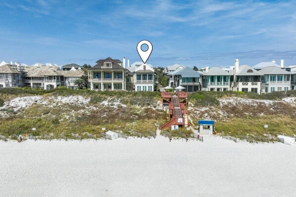 A beachfront property with multiple houses, a lifeguard tower, and a sandy beach.