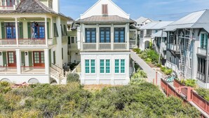 A coastal residential area with multiple houses featuring balconies, a covered porch, and a staircase leading to the upper floors.