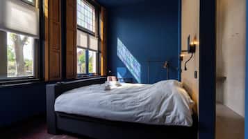 Un dormitorio con una cama grande, una ventana con persianas y una pantalla de proyección en la pared.