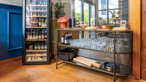 Zona de bar con vitrina refrigerada y estantes llenos de botellas y copas.