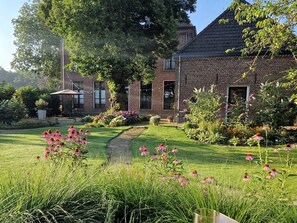 Ein Haus aus Ziegelsteinen mit Garten, Rasen und einem Weg.