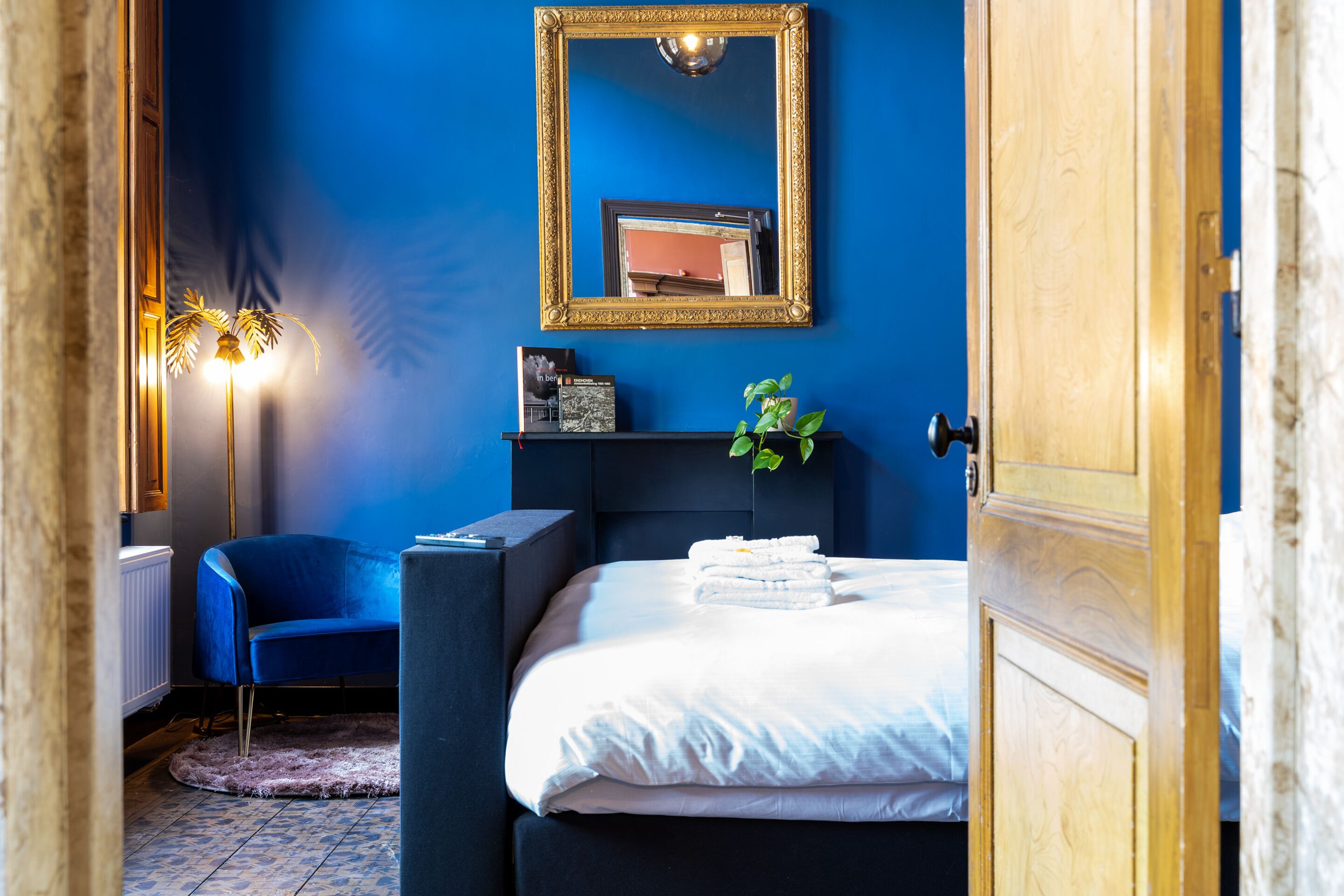 Une chambre à coucher avec un lit, une chaise, un miroir et une plante.