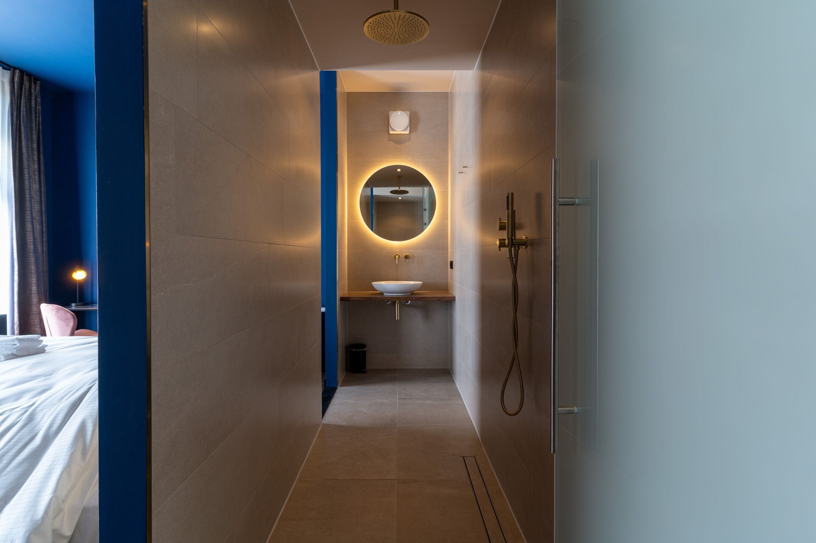 A modern bathroom with a round mirror, a sink, and a shower.