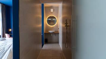 A modern bathroom with a round mirror, a sink, and a shower.