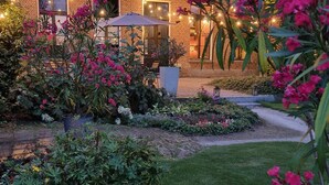 Une maison en briques avec un jardin, un espace salon extérieur et des guirlandes lumineuses.