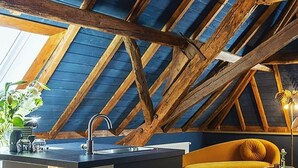 Una cocina moderna con una isla central, vigas de madera y un sofá amarillo.