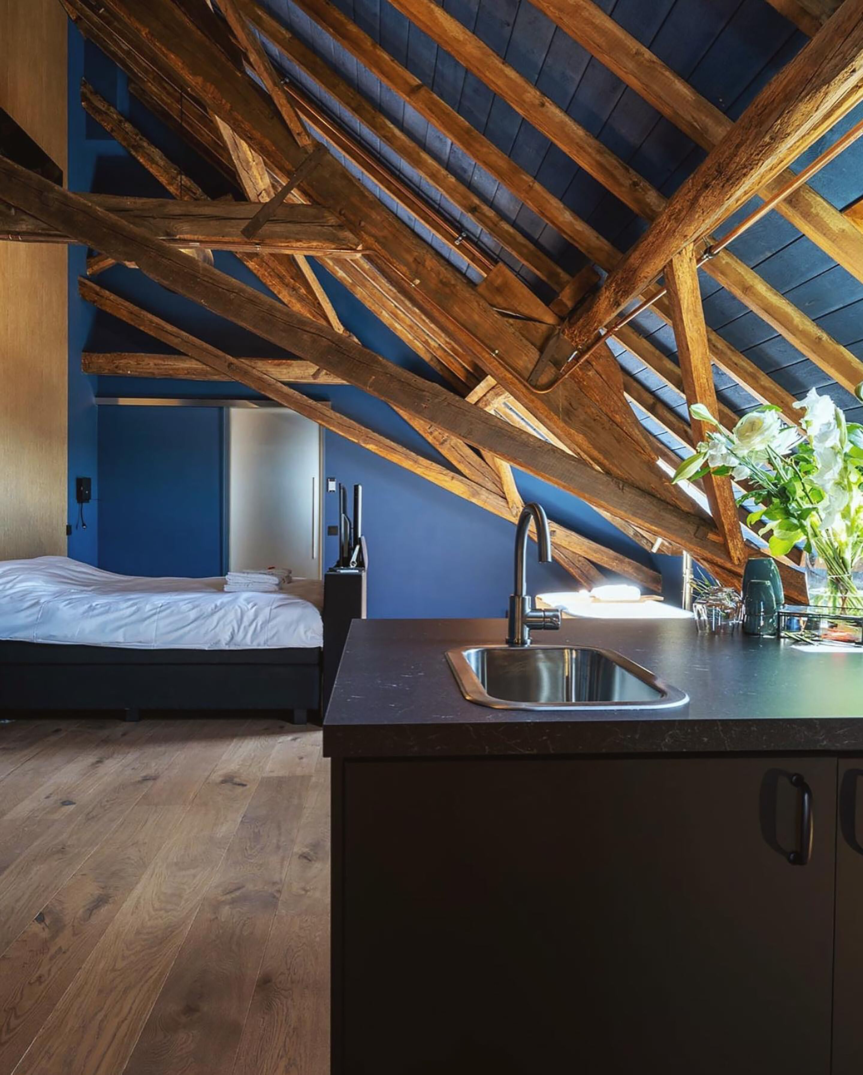 A bedroom with a wooden ceiling, a bed, and a nightstand.