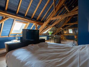 Ein Schlafzimmer mit einem großen Bett, einem Fernseher, einem Waschbecken und einer kleinen Küchenzeile.