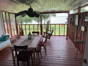 Un espace extérieur abrité, aménagé pour prendre les repas, avec une table et des chaises, un luminaire suspendu et une vue sur l’extérieur.