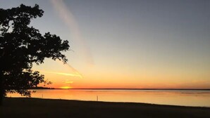A sunset over a calm body of water with a tree silhouette on the left. - Lakefront Cozy Cottage (Breckenridge)