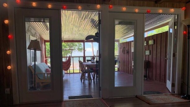 A room with a glass door leading to an outdoor area with a hammock and a table. - Lakefront Cozy Cottage (Breckenridge)