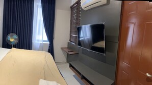 A hotel room with a bed, a TV, a fan, and a window with curtains. - Luxurious VI condo (Lagos)