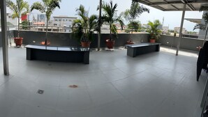 A rooftop terrace with potted plants, a bench, and a view of the cityscape. - Luxurious VI condo (Lagos)