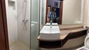 A bathroom with a glass shower enclosure, a white sink, and a toilet. - Luxurious VI condo (Lagos)