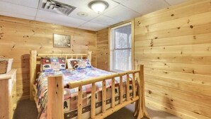 A wooden cabin bedroom with a bed, a window, and a ceiling vent. - Valley View in Shagbark (Sevierville)