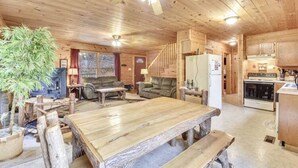 A wooden cabin interior with a dining table, sofas, a staircase, and a kitchen area. - Valley View in Shagbark (Sevierville)