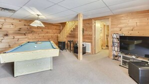 A pool table in a room with wooden walls and a carpeted floor. - Valley View in Shagbark (Sevierville)
