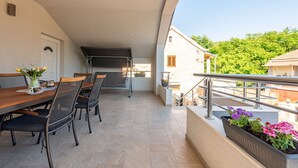An outdoor dining area with a table and chairs, a grill, and a view of the surrounding buildings and greenery. - Villa Izvor Zadarvillas (Skradin)