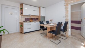 A modern kitchen with white cabinets, a wooden dining table, and black chairs. - Villa Izvor Zadarvillas (Skradin)