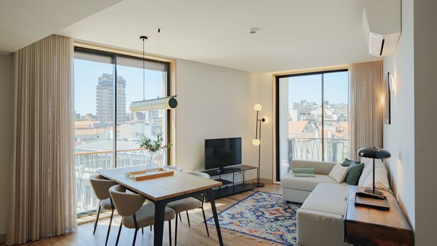 Una sala de estar moderna con comedor, ventanas amplias, televisor de pantalla plana y sofá.