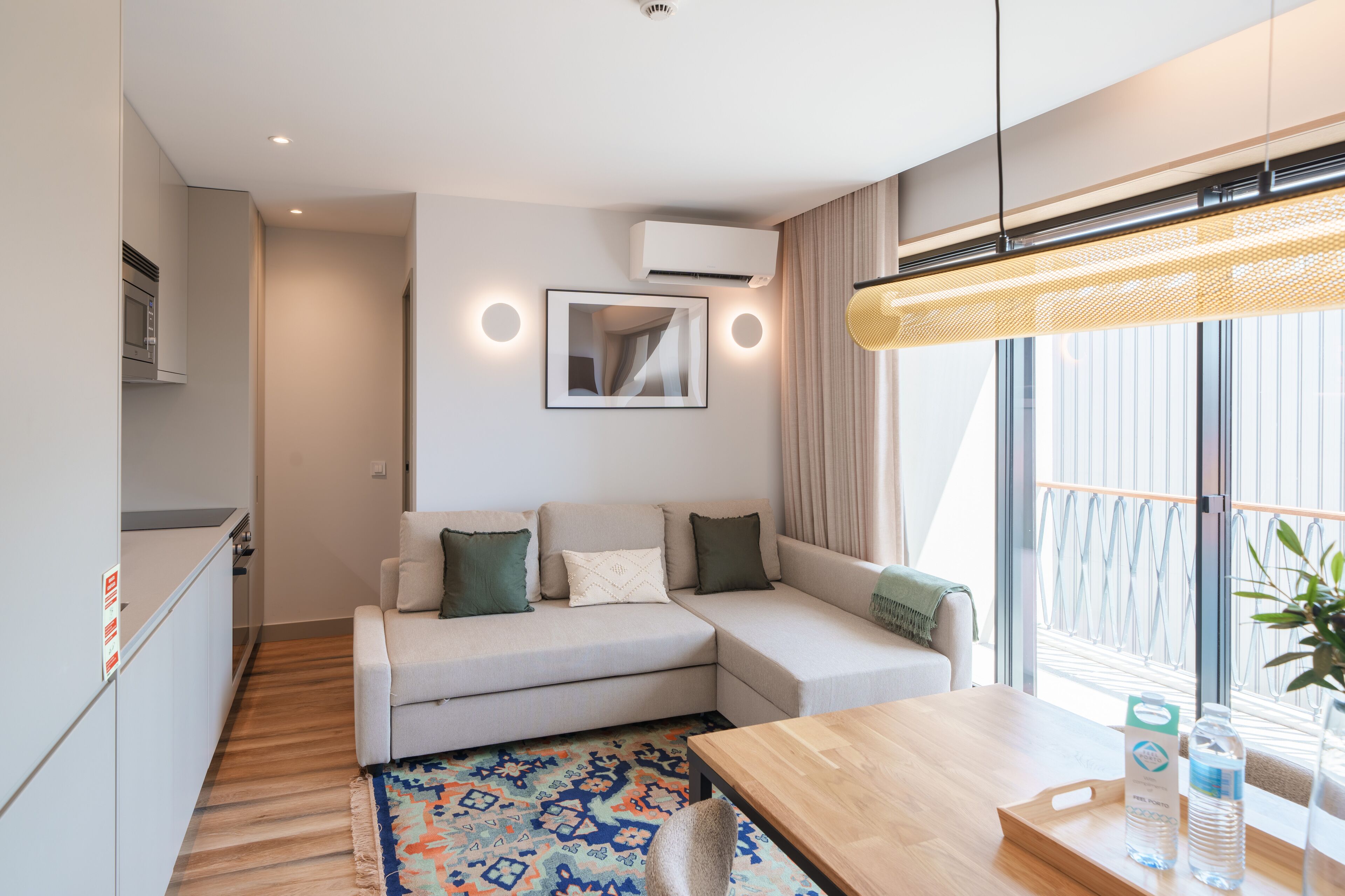 A modern living room with a sofa, a dining table, and a kitchen area.