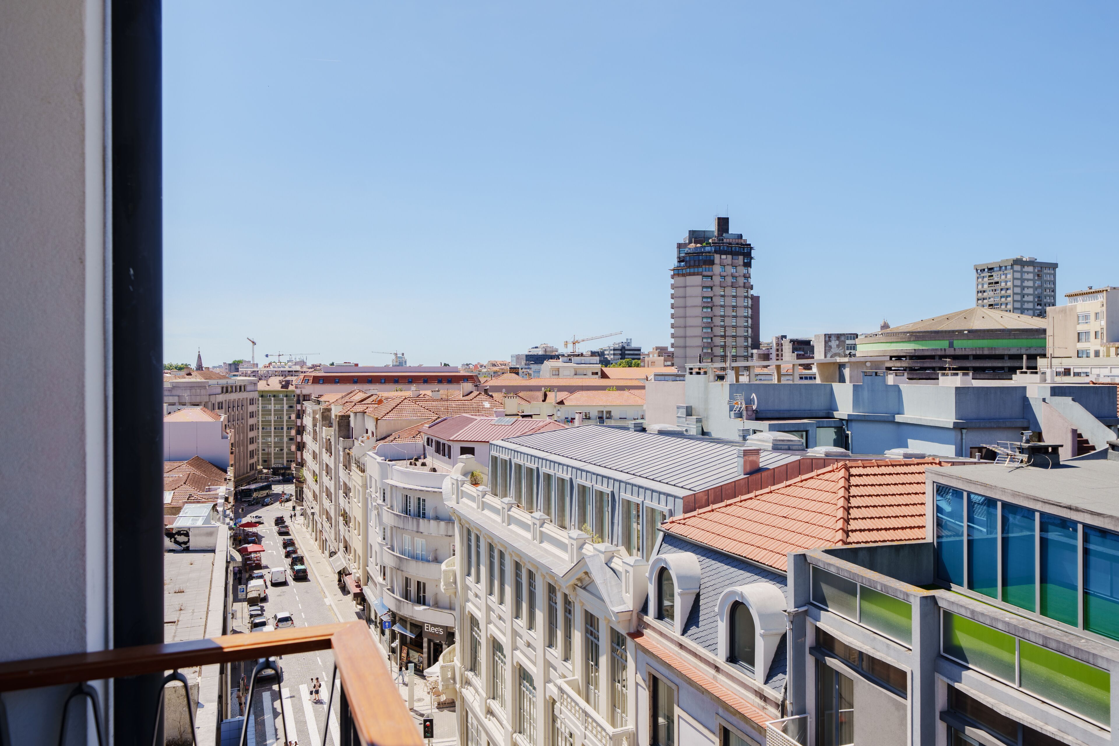 A cityscape with a mix of modern and traditional architecture, including a prominent building with a green roof and a tall structure with a unique design.