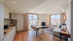 Un apartamento moderno con cocina, comedor y sala de estar. Cuenta con un amplio ventanal con vista a la ciudad, un televisor de pantalla plana y un sofá.