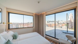 Habitación de hotel con dos camas, ventanas amplias y vista a la ciudad.