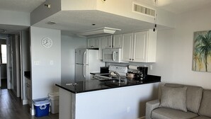 A modern kitchen with white cabinets, a black countertop, and a built-in oven.