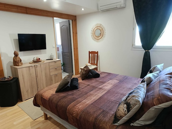 Ein Schlafzimmer mit einem Bett, einem Holzschrank, einem Fernseher und einer Wanddekoration.