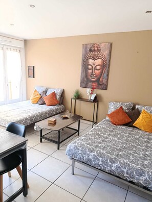 Ett rum med två soffor, ett litet bord, en stol och en målning av Buddha på väggen.