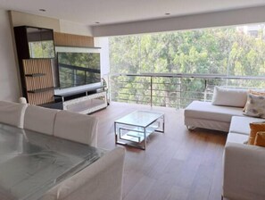 Relax in a spacious living room with a large flat-screen TV, comfortable seating area, and a glass coffee table.