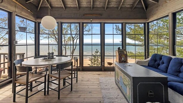 A wooden interior with a large window overlooking a beach.