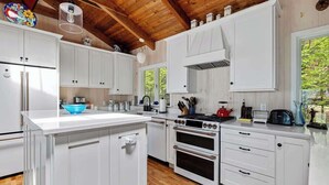 A kitchen with white cabinets, a central island, a stove, and a window.