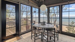 A room with large windows, a round table, and chairs.