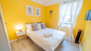 A bedroom with a bed, bedside table, and a window with curtains. - [Covent Garden-Fitzrovia]Central London Apartment (London)
