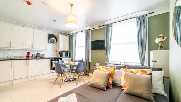 A modern hotel room with a kitchenette, a dining area, and a large bed with multiple pillows. - [Covent Garden-Fitzrovia]Central London Apartment (London)