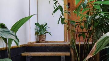 Una escalera de madera que conduce a una habitación con puerta de madera, rodeada de exuberante follaje.