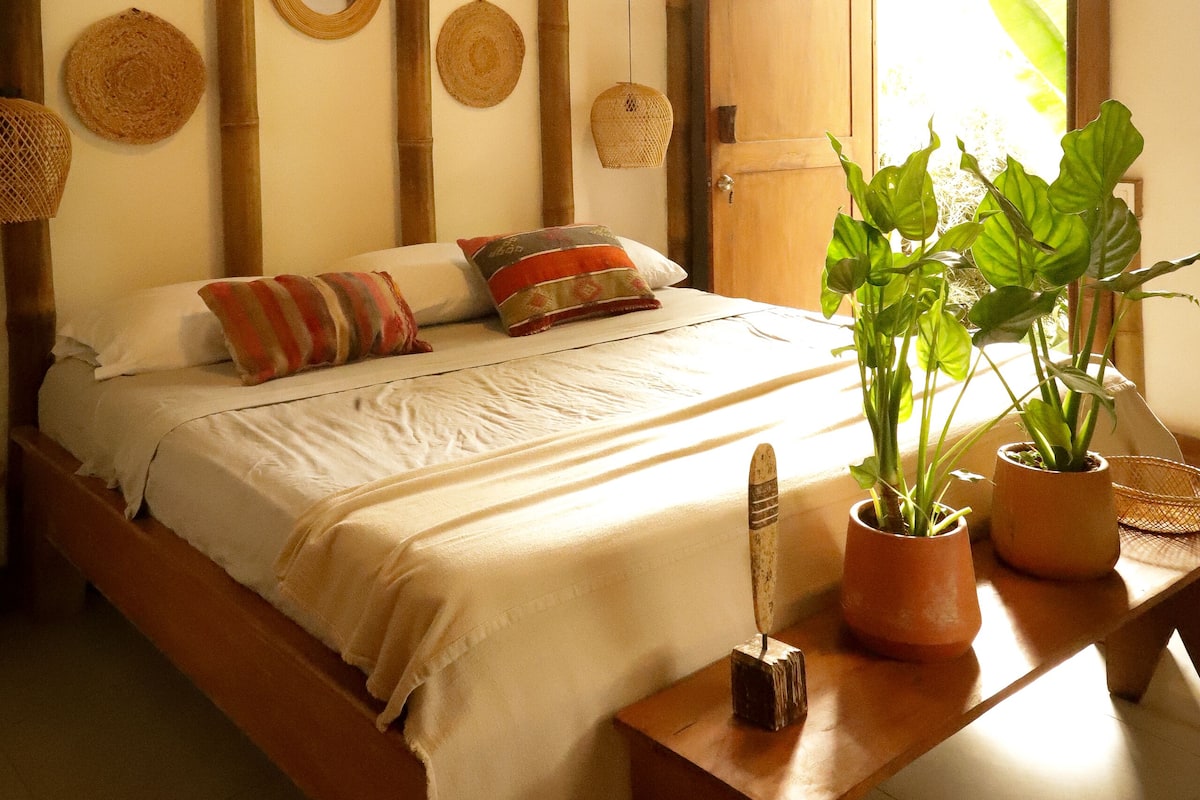 Een kamer met een bed, een houten tafel en een deur.