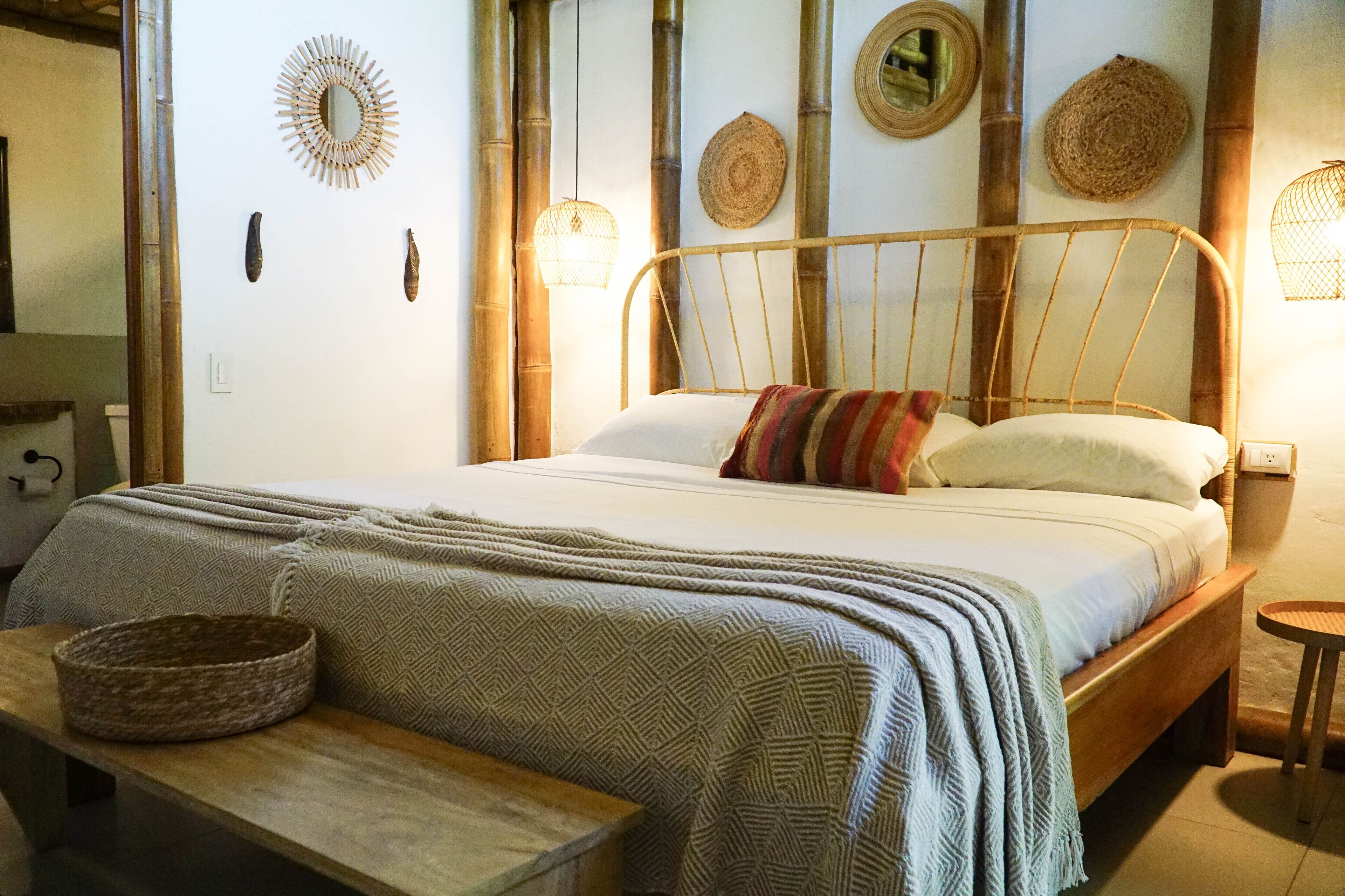 A bed with a wooden frame, a bedside table with a basket, and wall decor including woven baskets and a mirror.