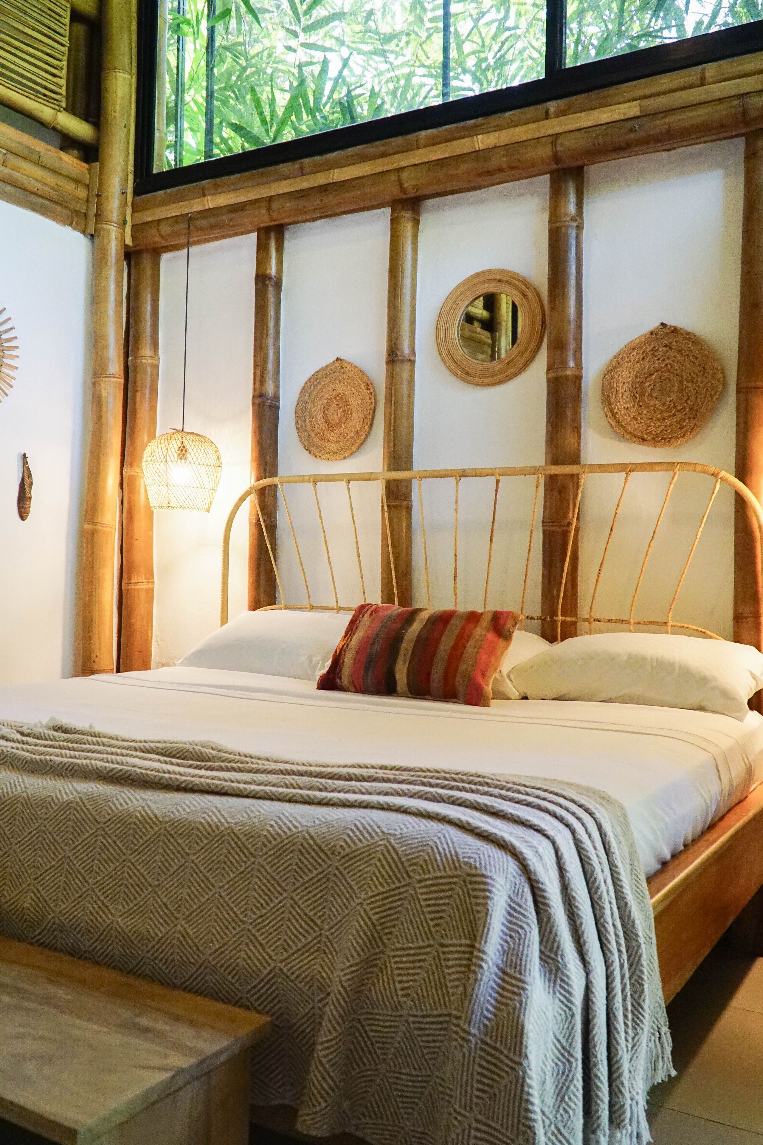 A bed with a woven headboard, a bedside lamp, and a woven wall hanging.